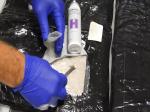 Funkcjonariusz Działu Granicznego Realizacji przy użyciu narkotestu sprawdza podejrzaną substancję przewożoną w bagażu przez obywatela Grecji.