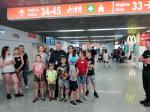 Grupa dzieci wraz z opiekunami i funkcjonariuszem na lotnisku.