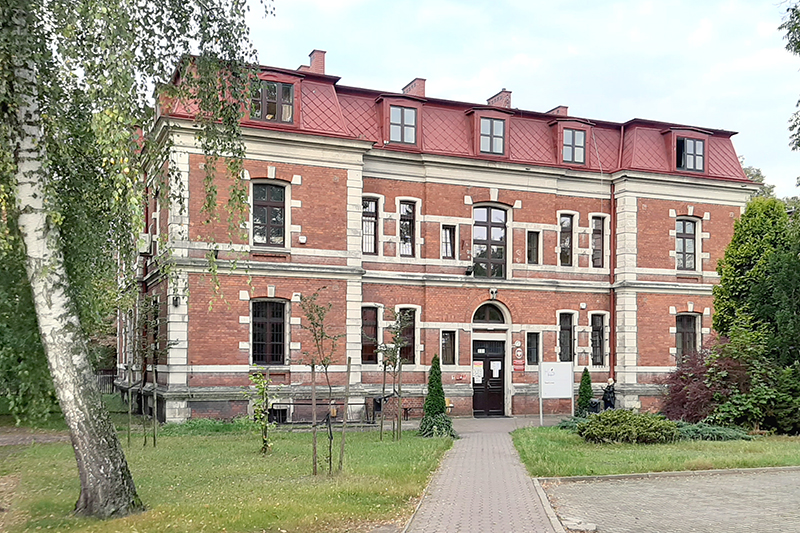Budynek Urzędu Skarbowego w Żyrardowie. Przed budynkiem trawnik, drzewa i chodnik.