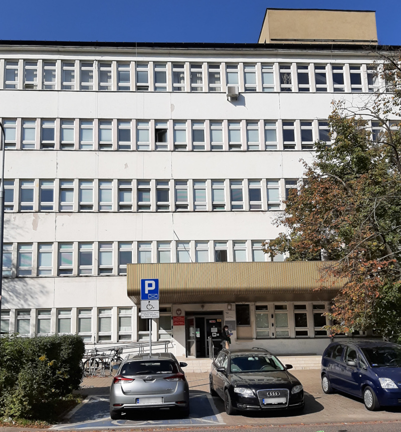 Budynek Urzędu Skarbowego Warszawa-Ursynów. Przed budynkiem parking, a nim kilka samochodów.