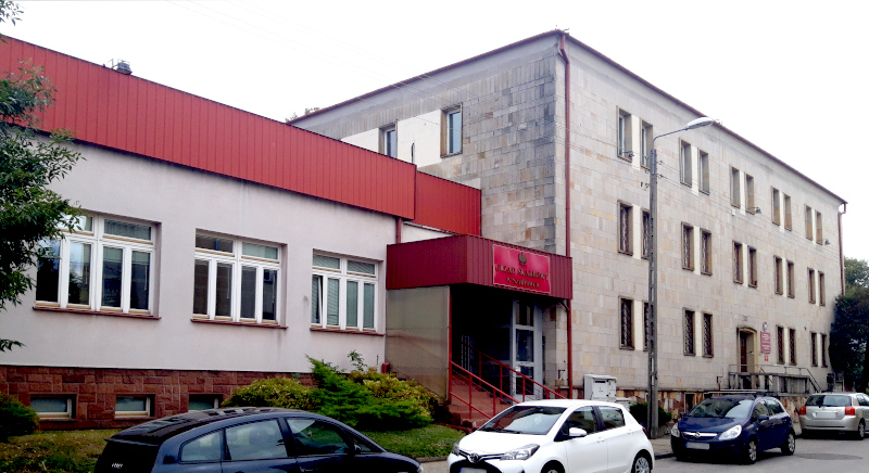Budynek Urzędu Skarbowego w Szydłowcu. Przed budynkiem parking i kilka samochodów.