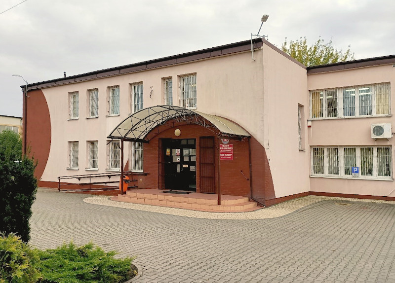 Budynek Urzędu Skarbowego w Gostyninie. Przed budynkiem parking i krzewy.