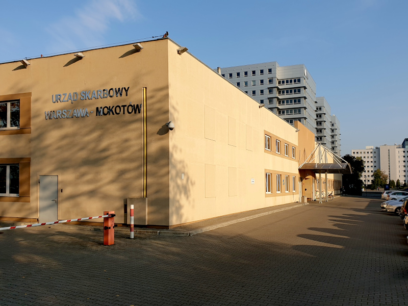 Budynek Urzędu Skarbowego Warszawa-Mokotów. Przed budynkiem parking i samochody.