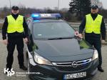 Dwóch funkcjonariuszy przy samochodzie służbowym
