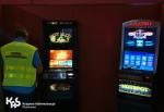 Funkcjonariusz mazowieckiej Służby Celno-Skarbowej stoi w kontrolowanym pomieszczeniu, w którym znajdują się dwa automaty do gier hazardowych