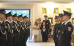 Środkiem w kościele stoi szpaler z funkcjonariuszy Kompanii Honorowej oraz młoda para i dwójka dzieci trzymająca w rękach kwiatki i obrączki