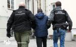 Dwóch funkcjonariuszy prowadzi zatrzymanego