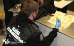 Funkcjonariusze Służby Celno-Skarbowej kładą na blacie owalne kapsułki kokainy, które przemycał Nigeryjczyk   