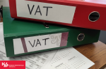 Dwa segregatory z napisem VAT leżą na biurku.