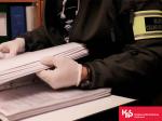 Funkcjonariusz Służby Celno-Skarbowej przegląda segregator z dokumentami.