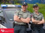 Funkcjonariusz i funkcjonariuszka SCS przy samochodzie służbowym
