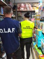 Funkcjonariusz Służby Celno-Skarbowej i mężczyzna z Europejskiego Urzędu Przeciwdziałania Nadużyciom podczas kontroli stoiska z zabawkami 