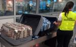 Funkcjonariuszka Służby Celno Skarbowej kontroluje walizki wypełnione papierosami