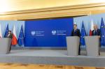 Minister finansów Andrzej Domański, minister zdrowia Izabela Leszczyna, wiceminister finansów Jarosław Neneman stoją za mównicami, w tle flagi Polski i UE