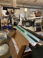 Urządzenia do produkcji papierosów oraz duży karton z nielegalnie wyprodukowanymi papierosami.