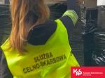 Funkcjonariusz Służby Celno-Skarbowej przeszukuje kartony