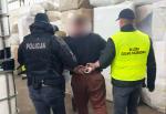 Funkcjonariusze policji i służby celno-skarbowej prowadzą zatrzymanego mężczyznę z założonymi kajdankami