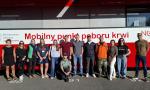 Zdjęcie grupowe krwiodawców przed ambulansem.
