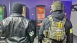 Fotografia przedstawia dwóch funkcjonariuszy policji i Służby Celno-Skarbowej w pomieszczeniu z automatami. 
