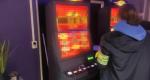 Kobieta z opaską z napisem Służba Celno-Skarbowa na ręce stoi przy automatach do gry.