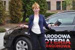 Uśmiechnięta pani Beata - laureatka marcowego losowania Opla Astry na tle wylosowanego samochodu