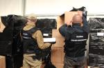 Funkcjonariusze celno-skarbowi dokonują oględzin kartonowych opakowań, w których znajdowały się nielegalne papierosy