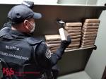 Funkcjonariusz Krajowej Administracji Skarbowej sprawdza prostokątne szczelnie opakowane paczki