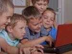 Czterech chłopców używa czerwonego laptopa