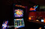 Automat do gry, a w tle fragment baru z neonem (napis bar i kieliszek z rurką).